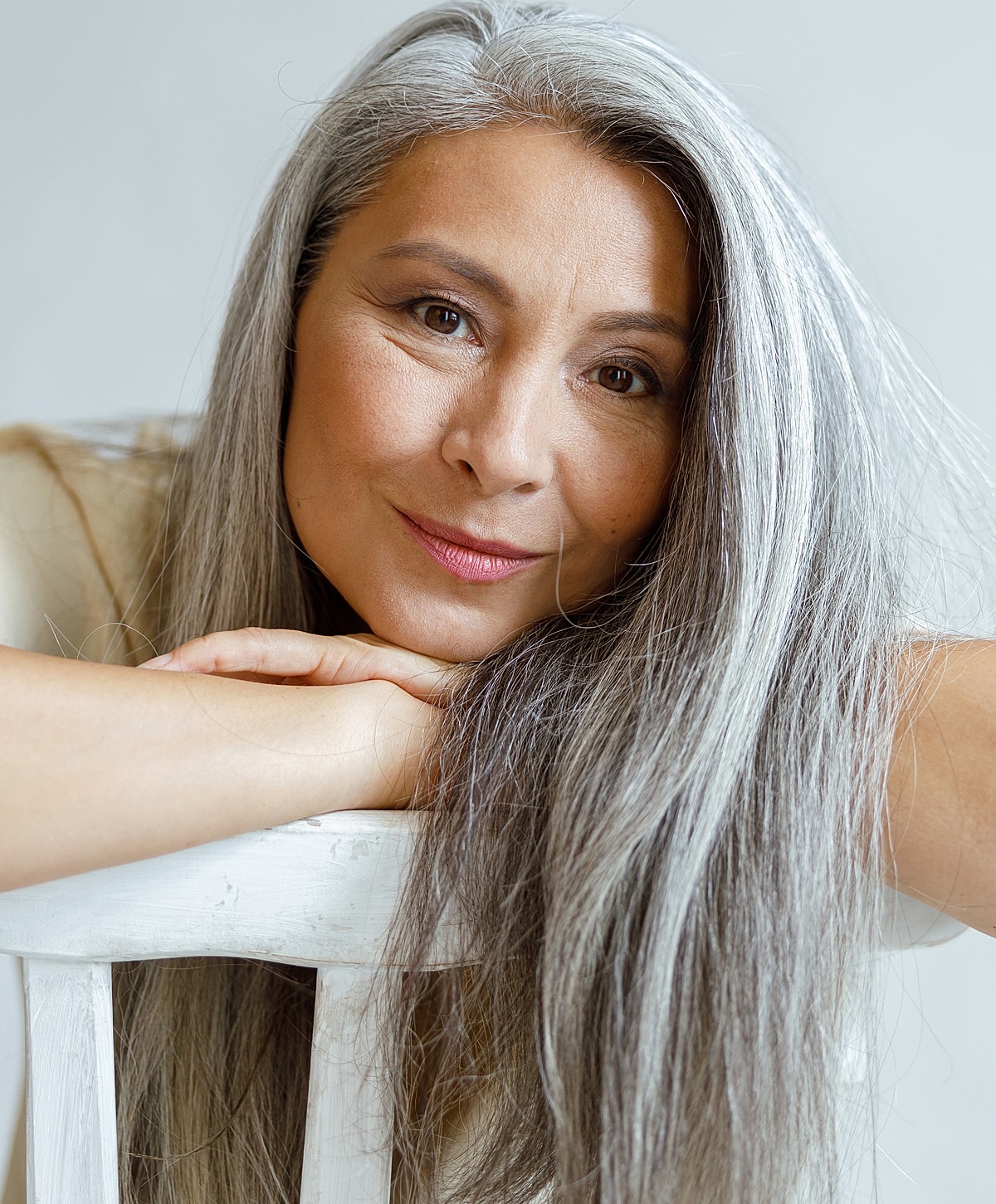 Smiling woman with long gray hair, resting chin.