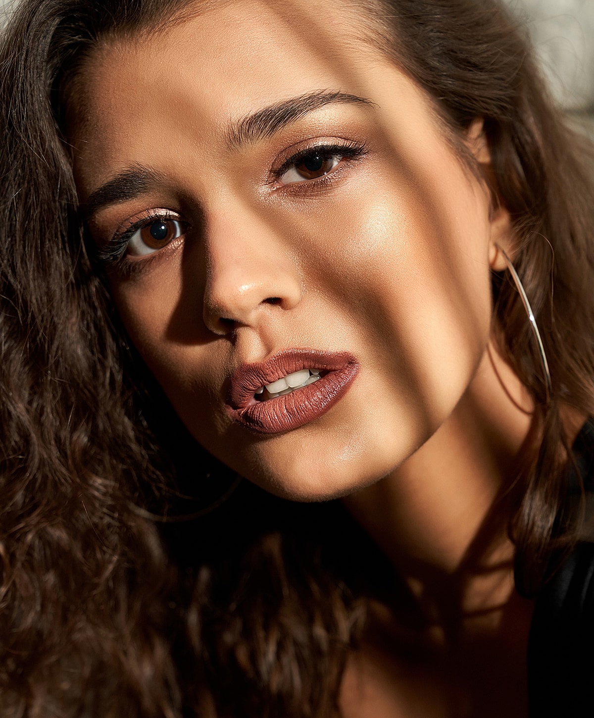 Close-up of woman with curly hair and makeup.
