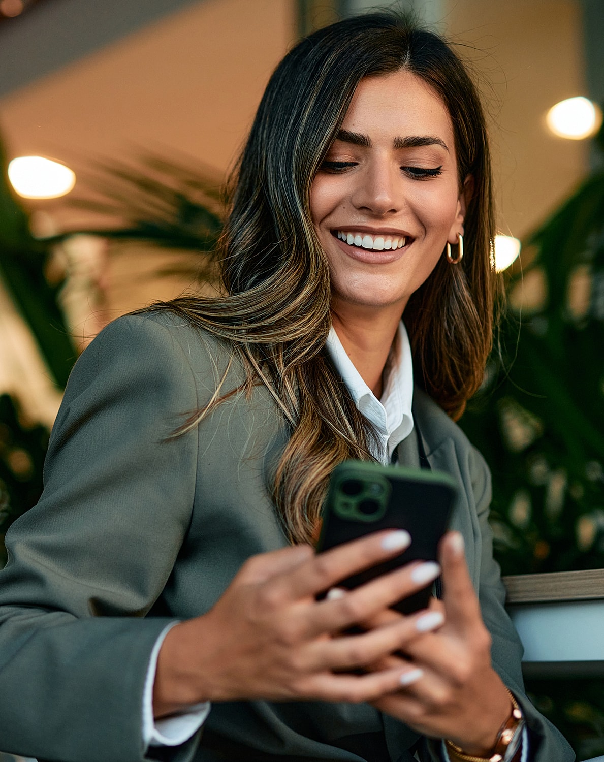Smiling woman using smartphone in professional setting.
