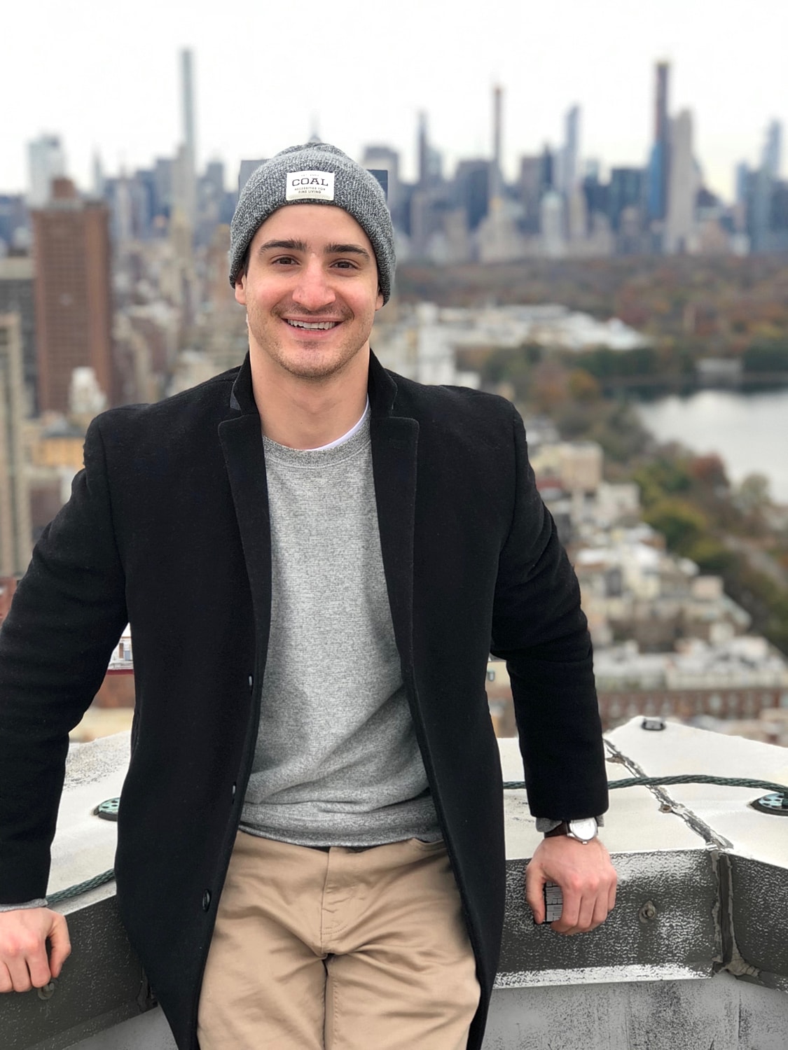 Man smiling on rooftop with city backdrop