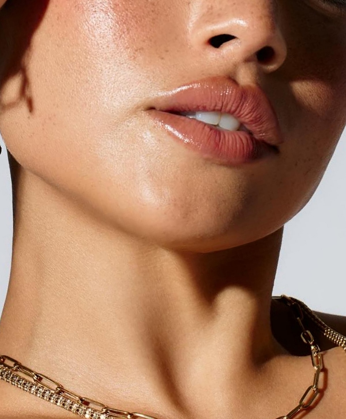 Close-up of lips and skin with jewelry.