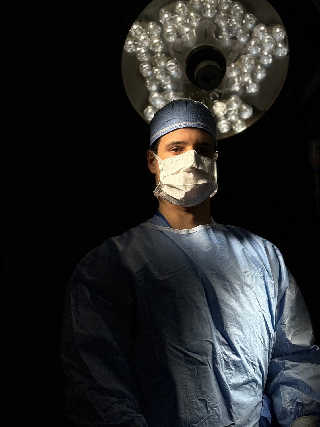 Surgeon in operating room with surgical lighting.
