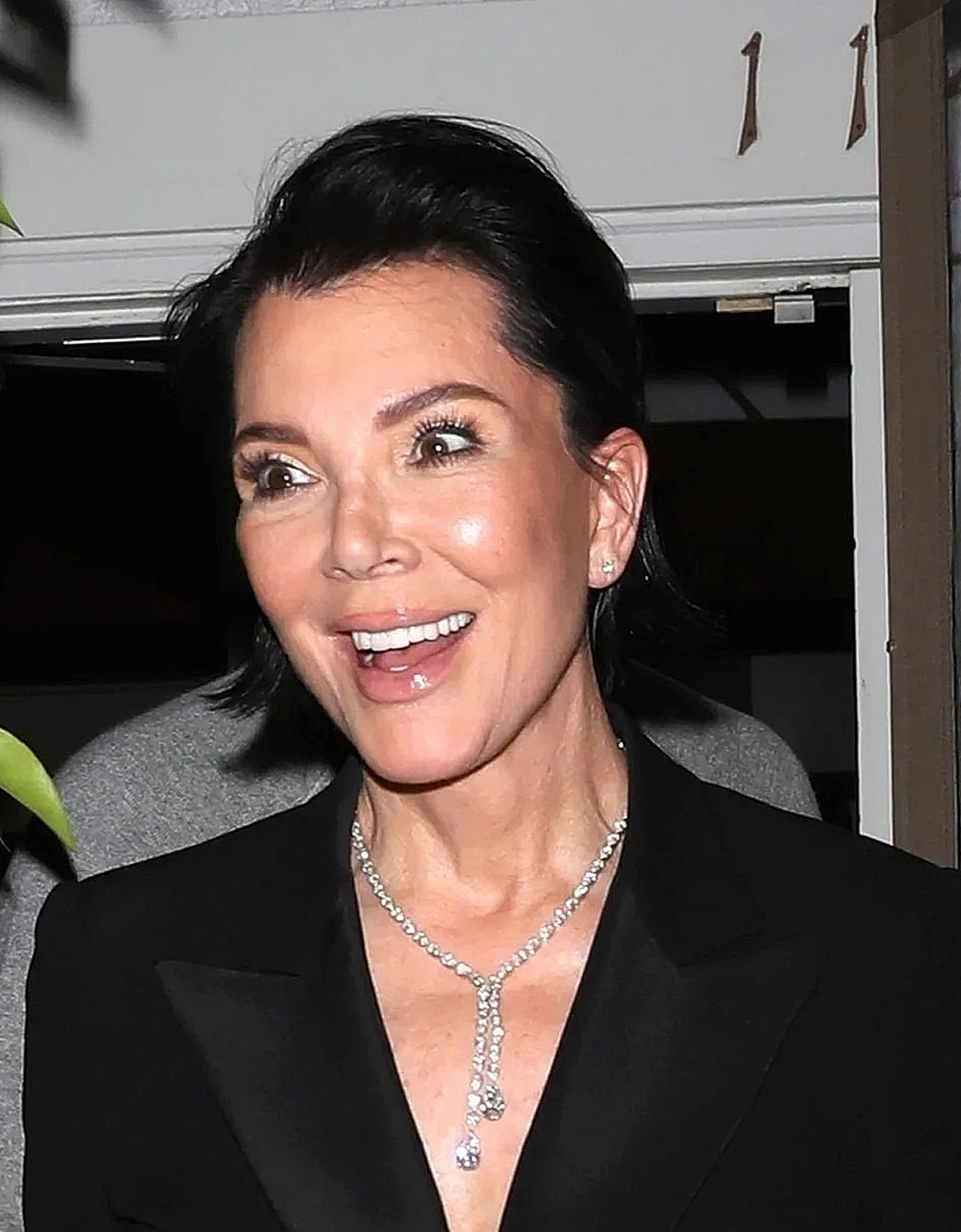 Smiling woman in elegant attire with necklace.