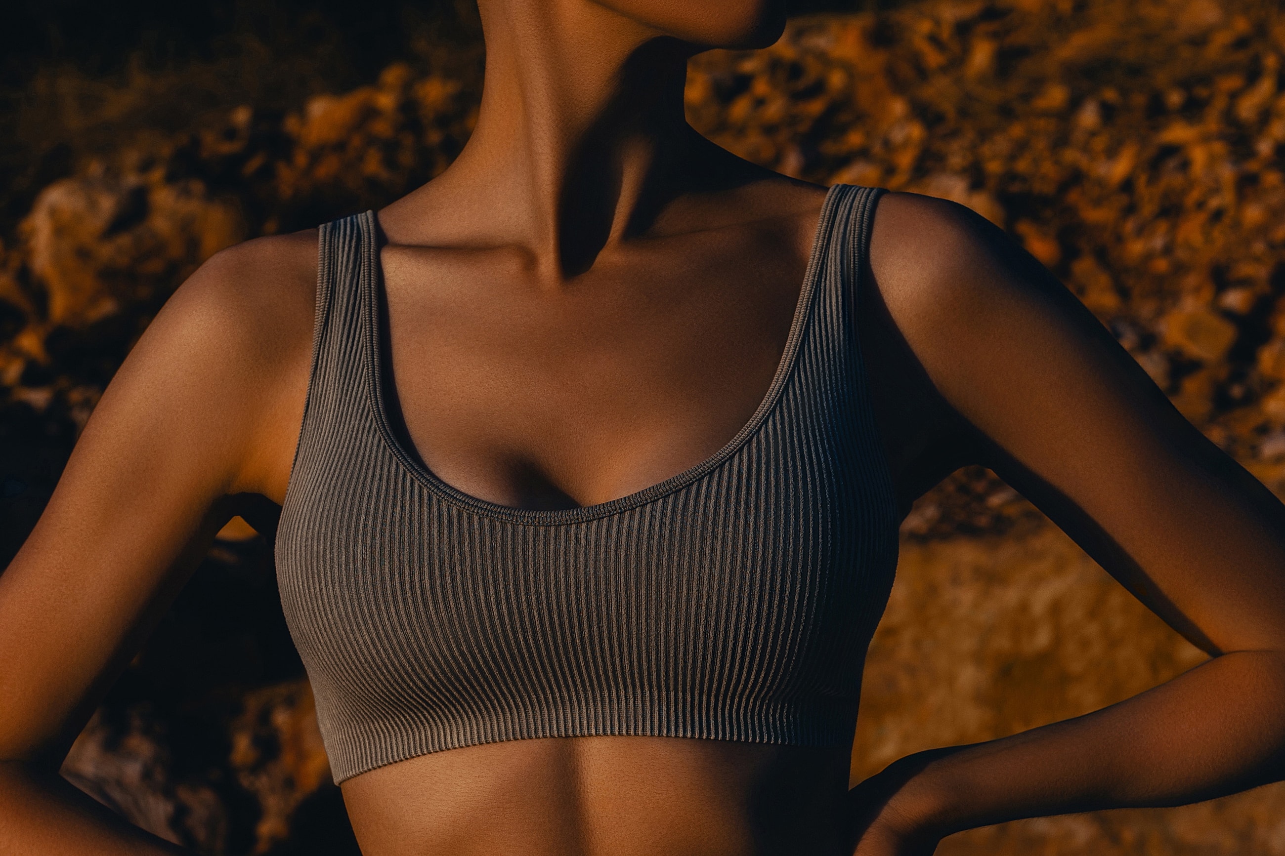 Model in ribbed sports bra against rocky background.