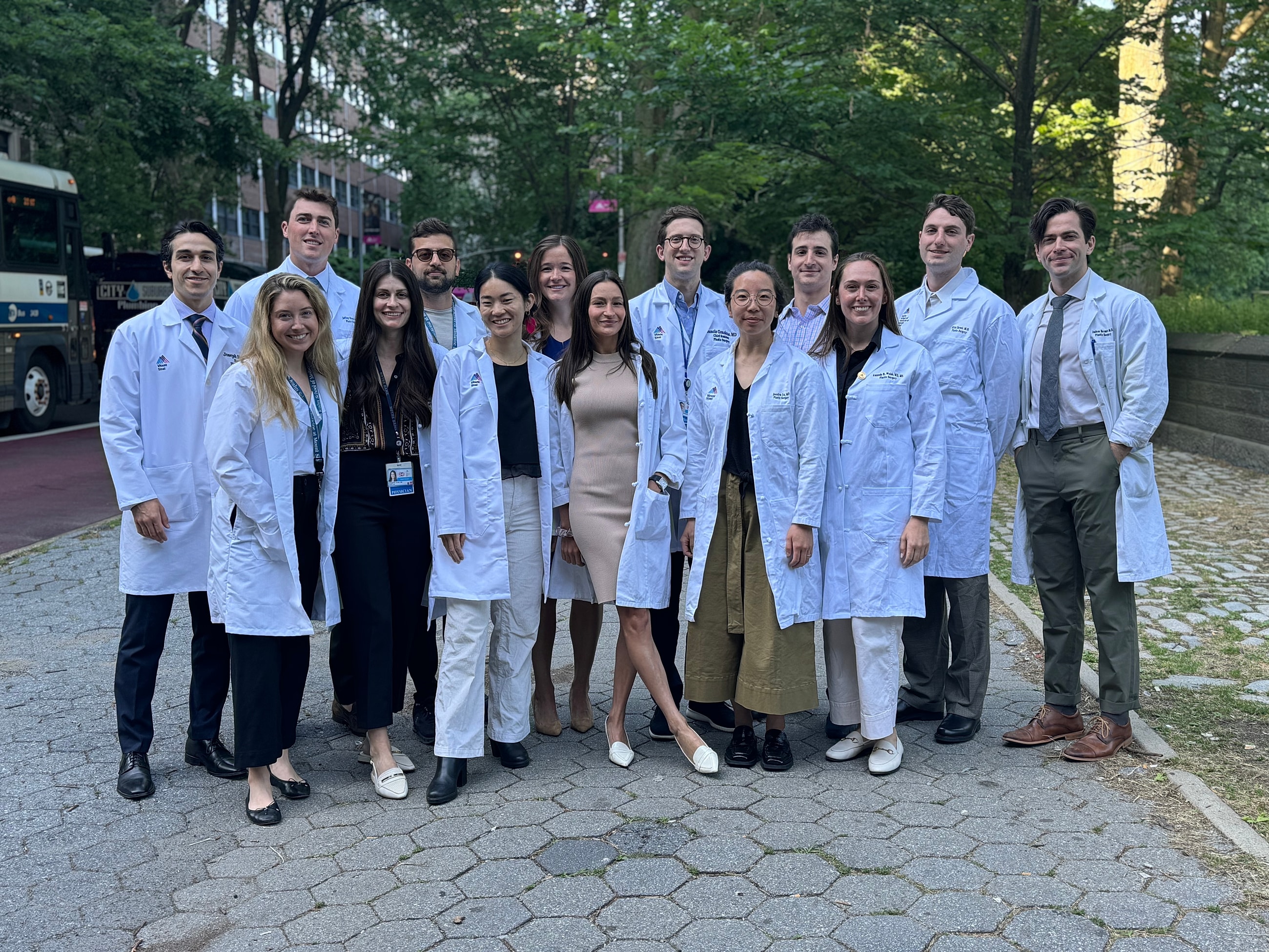 Medical students posing in white coats outdoors.
