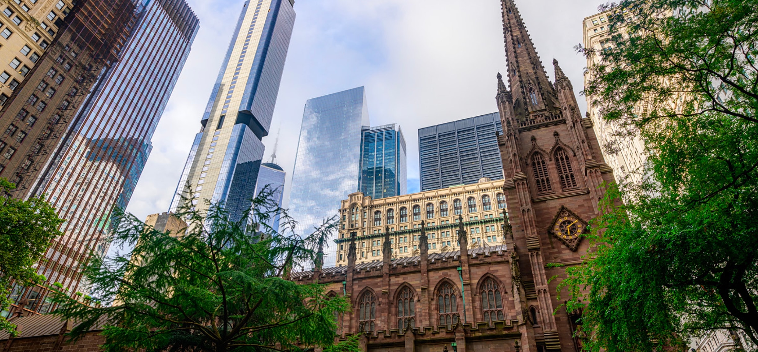 Historic church surrounded by modern skyscrapers.